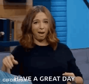 A Woman Is Sitting On A Couch With Her Mouth Open And Pointing At The Camera While Saying `` Have A Great Day '' . GIF