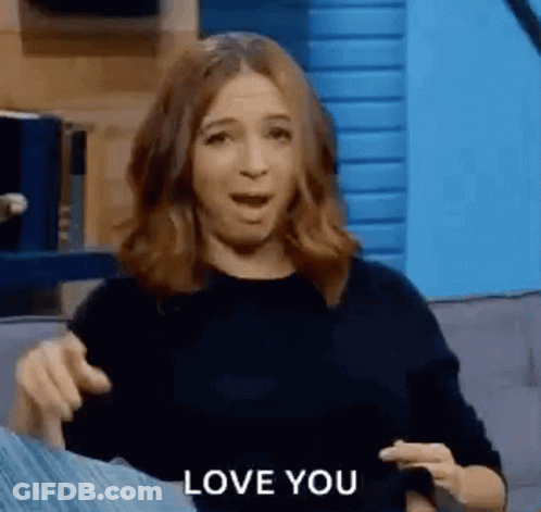 A Woman Is Sitting On A Couch With Her Mouth Open And Pointing At The Camera While Saying `` I Love You '' . GIF