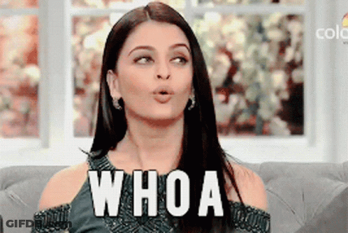 A Woman Is Sitting On A Couch With Her Mouth Open And The Word Whoa Written On Her Face GIF