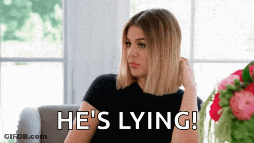 A Woman Is Sitting On A Couch With The Words `` He 'S Lying '' Written On The Screen . GIF
