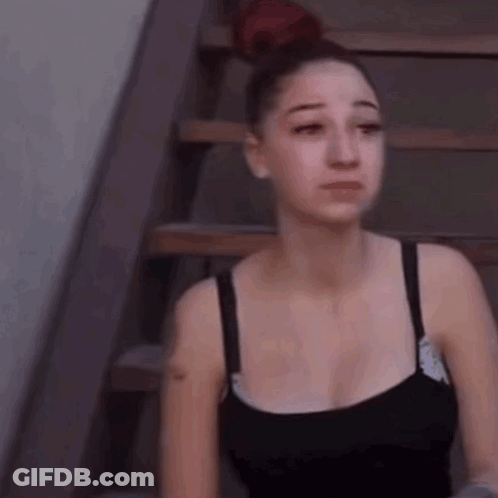 A Woman Is Sitting On A Set Of Stairs With Her Eyes Closed . GIF