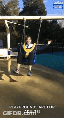 A Woman Is Sitting On A Swing At A Playground And Smiling . GIF
