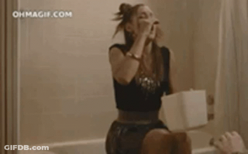 A Woman Is Sitting On A Toilet In A Bathroom With Blood On The Wall . GIF