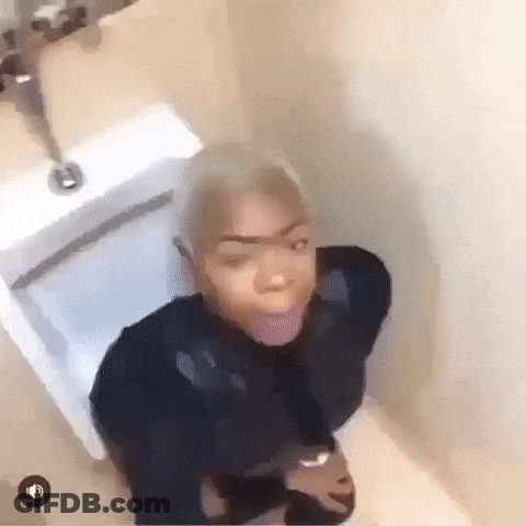 A Woman Is Sitting On A Toilet In A Bathroom With Her Tongue Out . GIF