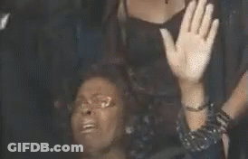 A Woman Is Sitting On The Floor With Her Hands In The Air And A Man Is Standing Behind Her . GIF