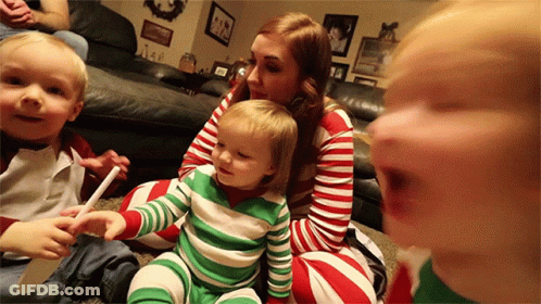 A Woman Is Sitting On The Floor With Two Children Wearing Striped Pajamas GIF