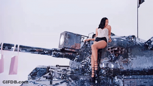 A Woman Is Sitting On Top Of A Giant Tank GIF