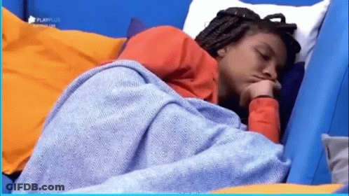 A Woman Is Sleeping In A Bed With A Blue Blanket On Her Head . GIF