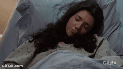 A Woman Is Sleeping In A Hospital Bed With Citytv On The Bottom GIF