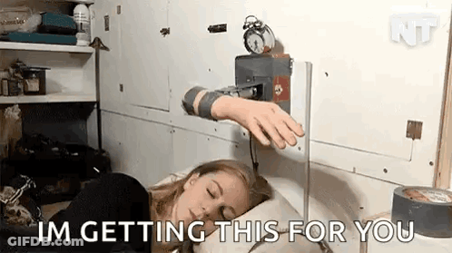 A Woman Is Sleeping In Bed With An Alarm Clock On The Wall Behind Her . GIF