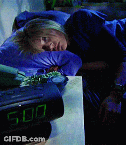A Woman Is Sleeping Next To An Alarm Clock That Shows The Time As 5:00 GIF
