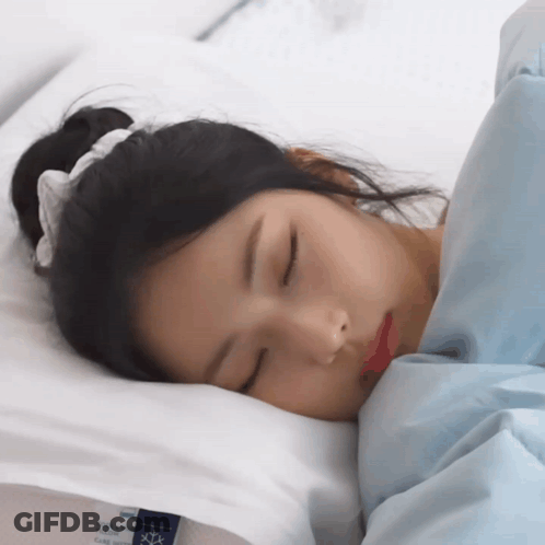 A Woman Is Sleeping On A Bed With A Pillow That Says Cool & Glow GIF