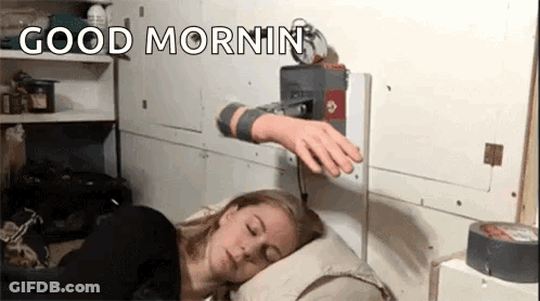 A Woman Is Sleeping On A Pillow With A Robotic Arm Reaching Out Towards Her . GIF