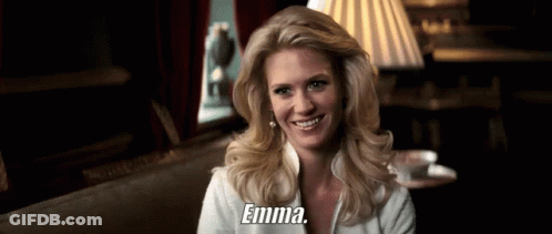 A Woman Is Smiling And Holding A Cup Of Coffee And The Word Emma Is On The Bottom Of Her Shirt . GIF