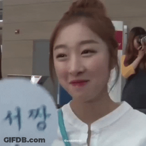 A Woman Is Smiling And Holding A Fan With Chinese Writing On It GIF