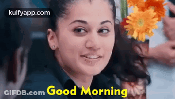 A Woman Is Smiling And Holding A Vase Of Flowers In Her Hand . GIF