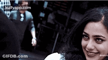 Smiling Woman Looking At Camera With Man In Background GIF