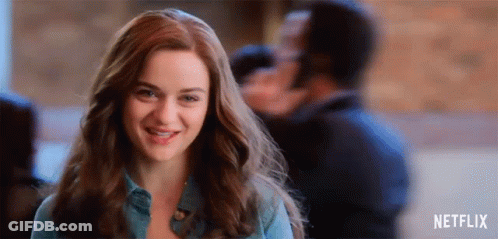 A Woman Is Smiling And Looking At The Camera While Standing In Front Of A Man . GIF