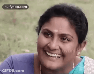 A Woman Is Smiling And Looking At The Camera While Wearing A Blue Shirt And A Blue Saree . GIF