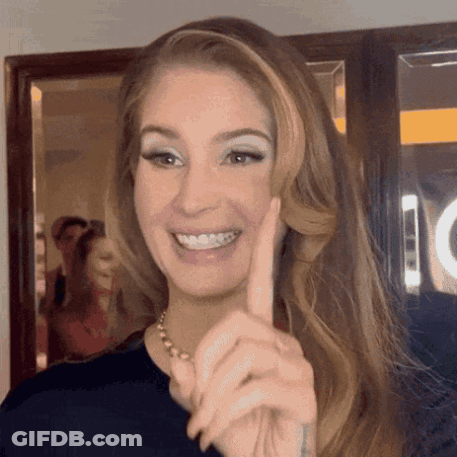 A Woman Is Smiling And Pointing At The Camera With Her Finger . GIF