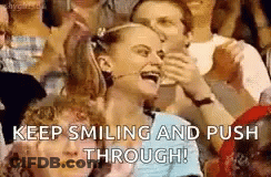A Woman Is Smiling And Pushing Through A Crowd Of People In A Stadium . GIF