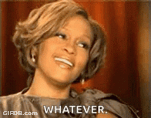 A Woman Is Smiling And Saying `` Whatever '' While Sitting In Front Of A Red Curtain . GIF