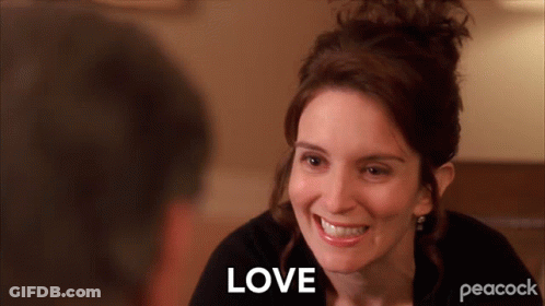 A Woman Is Smiling And The Word Love Is Visible Behind Her GIF