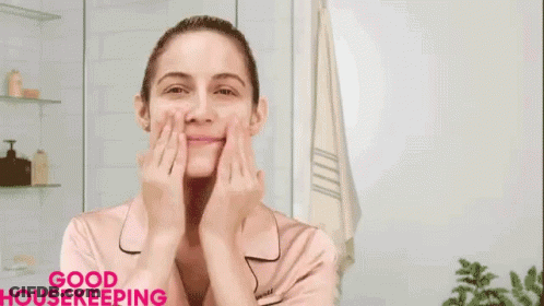 A Woman Is Smiling And Touching Her Face In Front Of A Clock That Says Anti-Aging Niacinamide Hyaluronic Acid GIF