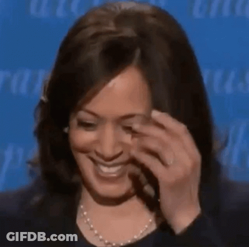 A Woman Is Smiling And Touching Her Face With Her Hand While Wearing A Pearl Necklace . GIF