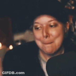 A Woman Is Smiling And Waving Her Hand In Front Of A Sign That Says Bye-Bye . GIF