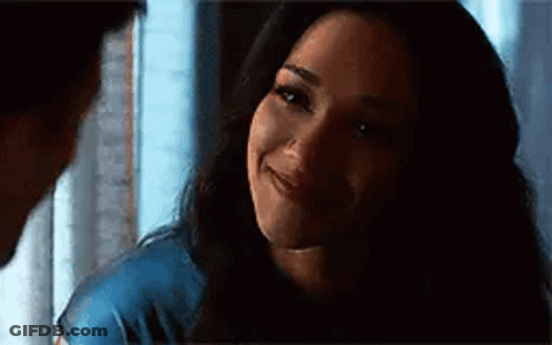 A Woman Is Smiling At A Man In A Dark Room While Looking At Him . GIF