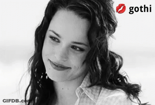 A Woman Is Smiling In A Black And White Photo With A Gothi Logo Behind Her GIF