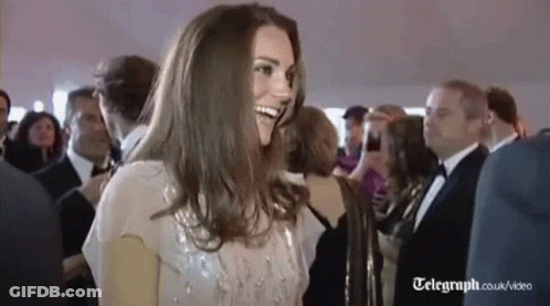 A Woman Is Smiling In A Crowd Of People At A Party . GIF