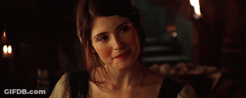 A Woman Is Smiling In A Dark Room With Candles In The Background GIF