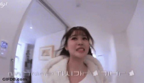 A Woman Is Smiling In A Hallway With Chinese Writing On The Bottom GIF