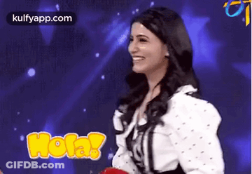 A Woman Is Smiling In Front Of A Blue Background While Holding A Red Balloon . GIF
