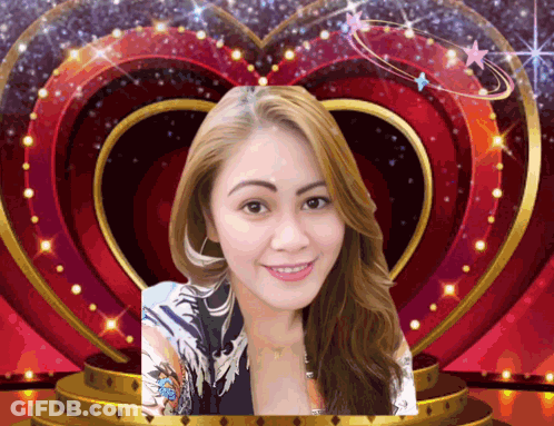 A Woman Is Smiling In Front Of A Heart Shaped Frame GIF