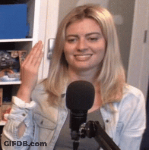 A Woman Is Smiling In Front Of A Microphone And Waving GIF