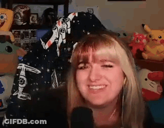 A Woman Is Smiling In Front Of A Microphone In A Room Filled With Toys . GIF