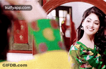 A Woman Is Smiling In Front Of A Mirror In A Room . GIF