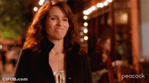 A Woman Is Smiling In Front Of A Peacock Ad GIF