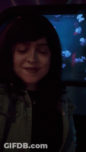 A Woman Is Smiling In Front Of A Screen That Says Shagarita On It GIF
