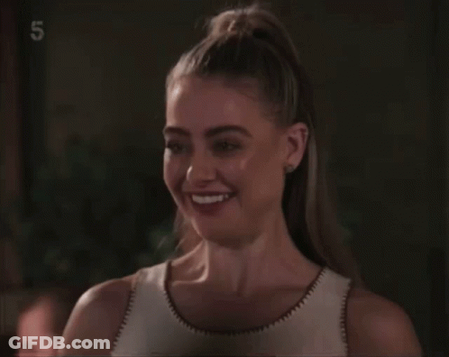 A Woman Is Smiling In Front Of A Screen With The Number 5 On It GIF