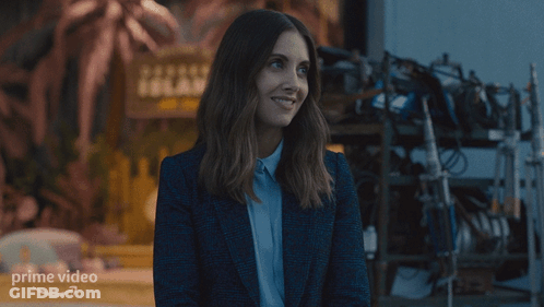 A Woman Is Smiling In Front Of A Sign For Prime Video GIF