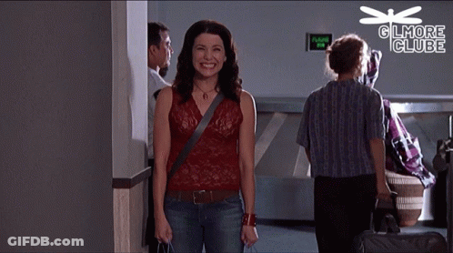 A Woman Is Smiling In Front Of A Sign That Says " Gilmore Club " GIF