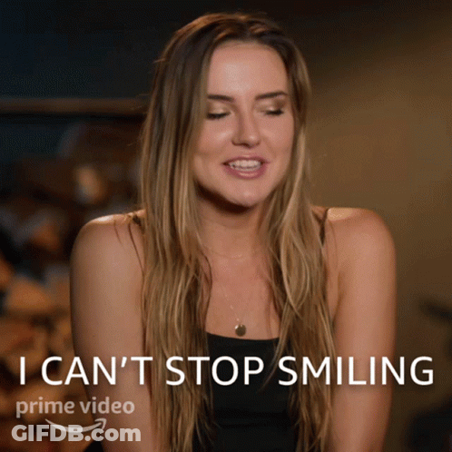 A Woman Is Smiling In Front Of A Sign That Says I Can 'T Stop Smiling Prime Video GIF