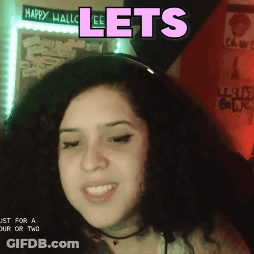 A Woman Is Smiling In Front Of A Sign That Says " Lets " GIF