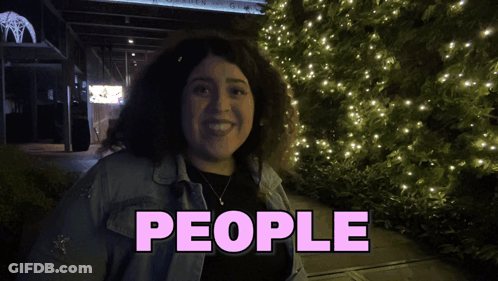 A Woman Is Smiling In Front Of A Sign That Says " People " GIF