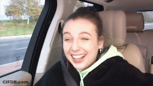 A Woman Is Smiling In The Back Seat Of A Car With A Seat Belt On GIF