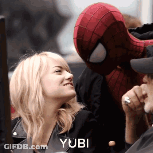 A Woman Is Smiling Next To A Man In A Spiderman Costume With The Word Yubi On The Bottom Right GIF